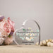 Heart-shaped glass plaque with printed text and floral design, placed on a surface with flowers and beads.