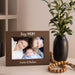 Wooden photo frame with family photo on a surface with a vase and beads in the background