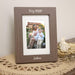 Wooden photo frame with a picture of a woman and child, resting on top of a placemat next to dried floral