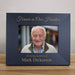 black photo frame with a portrait of an elderly man and personalized text on a wooden surface.