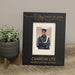 Graduation-themed photo frame with a picture of a graduate, placed on a surface with a plant in the background.