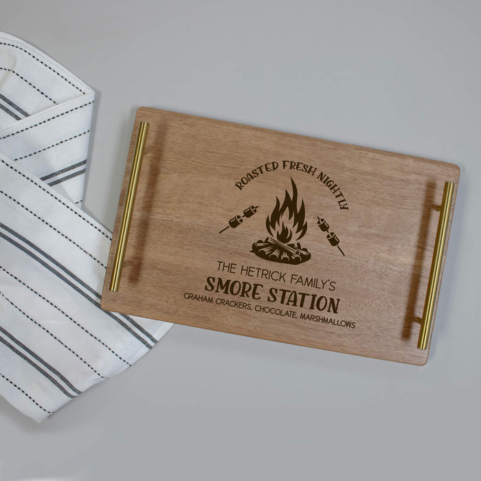 Wooden serving tray with engraved text "S'more Station" and campfire design on a gray surface