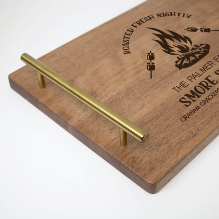 Wooden serving board with gold handle and engraving on a white background