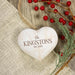 A heart-shaped wooden ornament with a rustic distressed finish, engraved with the text 'The KINGSTONS EST. 2025' in brown lettering.