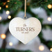A heart-shaped wooden Christmas ornament hanging from a tree branch with a twine loop. The ornament is cream-colored with brown engraved text reading 'The Turners' and an established year.