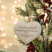 A heart-shaped wooden Christmas ornament engraved with 'Loved beyond words, missed beyond measure. Pearl Oesterling 1931 - 2025' hanging on a decorated tree branch with pine needles, red berries, and warm blurred lights in the background.