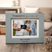 Horizontal light blue picture frame engraved with the phrase "Promoted to Grandma" in a living room setting