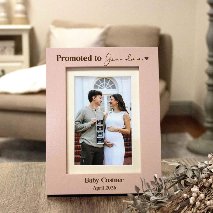 Light pink vertical photo frame that has "Promoted to Grandma" engraved in dark brown, photo inside showing a pregnant woman and man holding ultrasound pictures