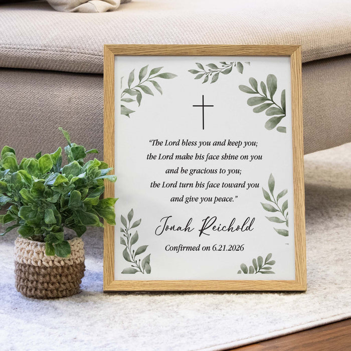 Framed print with a cross and text on a surface next to a plant