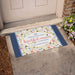 Decorative doormat with floral design and "There are so many beautiful reasons to be happy" text on a doorstep.