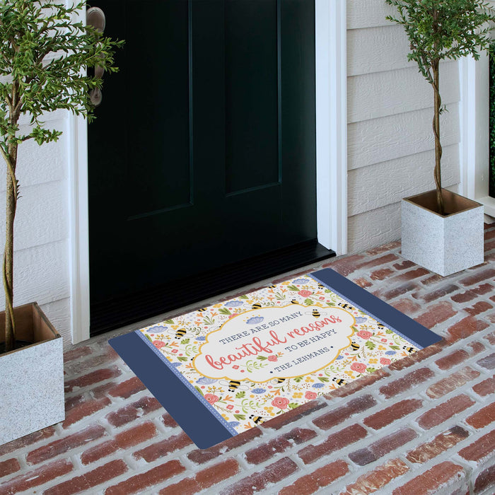 Decorative doormat with floral design and text on a brick porch.