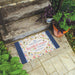 Decorative doormat with motivational quote on a stone step outdoors