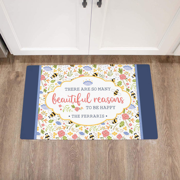 Decorative doormat with floral design and text on a wooden floor.
