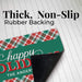 A holiday-themed doormat with a green front, red and green plaid pattern, and black rubber backing, shown on a white wood plank background with text reading 'Thick, Non-Slip Rubber Backing'.