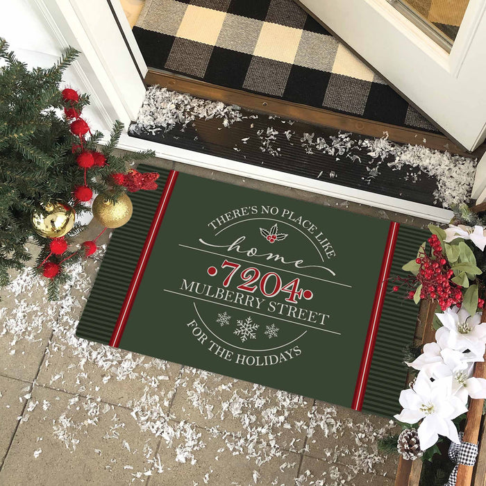 A dark green holiday-themed doormat with red and white text reading 'home "7204 MULBERRY STREET" FOR THE HOLIDAYS' is displayed on a front porch. The mat features dark green vertical stripes on the sides and red borders.