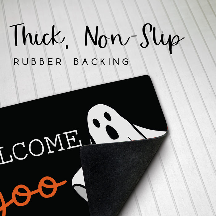A black Halloween-themed doormat with a white ghost graphic and partial 'Welcome' text, shown on a white paneled floor with the corner peeled up to reveal the rubber backing. Text at the top reads 'Thick, Non-Slip RUBBER BACKING'.