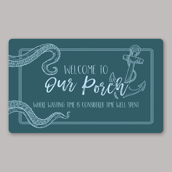 Teal nautical doormat with light blue text and anchor design on a gray background