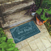 Decorative doormat with 'Welcome to Our Porch' text on a stone step with plants.