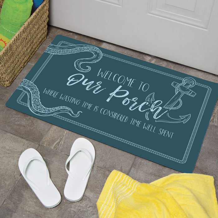 Doormat with 'Welcome to Our Porch' text on a floor with white sandals and a yellow towel.