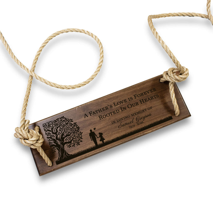 Wooden tree swing with engraved text and a tree design, hanging by a rope on a white background.