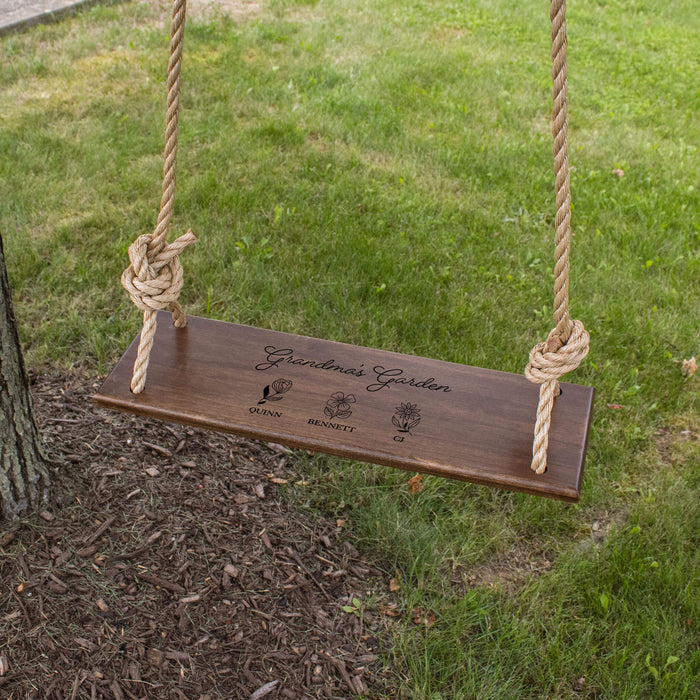 Wooden swing hanging from a tree that has a floral design engraved on it