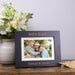 Personalized photo frame with a family picture on a wooden surface with flowers in the background