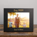 Black photo frame with 'Boy Mom' and boys' names engraved on it on a wooden table.