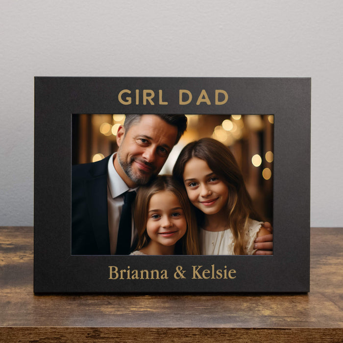 Black photo frame with a family portrait and 'Girl Dad' text on a wooden surface.