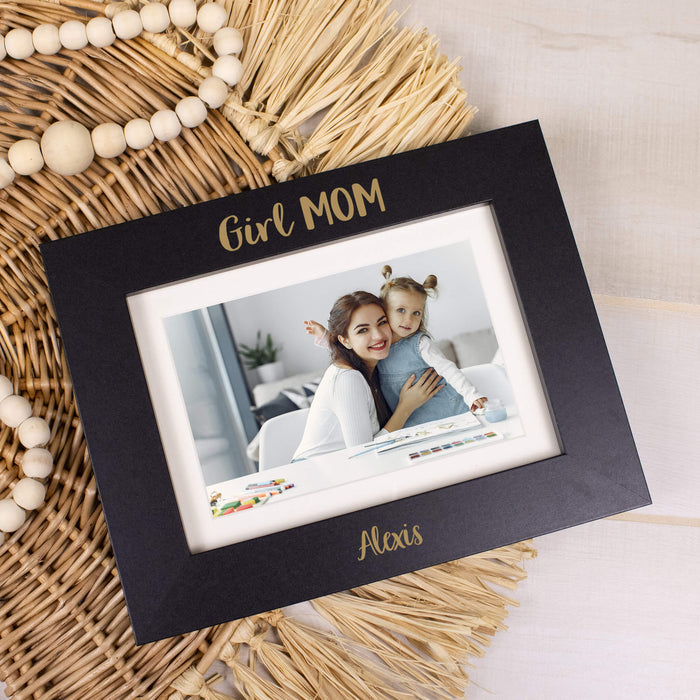Black photo frame with 'Girl MOM' text, featuring a photo of a woman and a child, on a wicker surface.