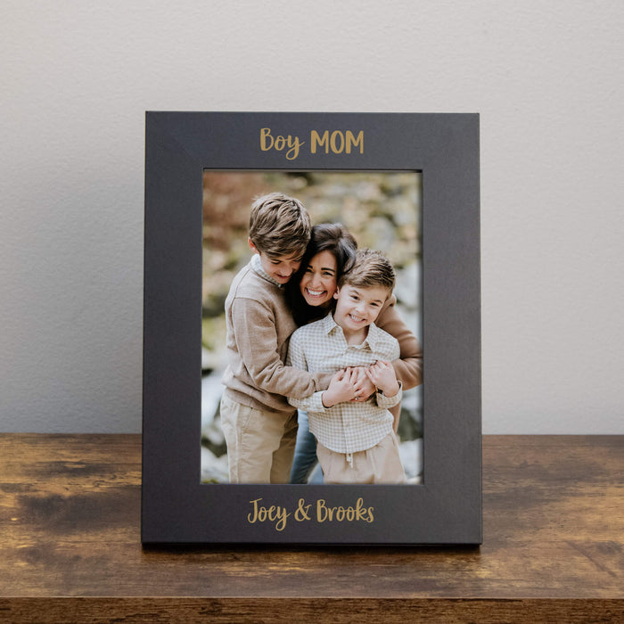 Black photo frame with a family photo and 'Boy MOM' text on a wooden table.