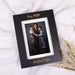 Black photo frame with a family portrait and "Boy Mom" engraved on it on a white surface