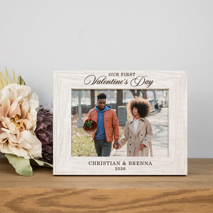 rustic white picture frame engraved with "Our First Valentine's Day" on top and the couples names and year at the bottom