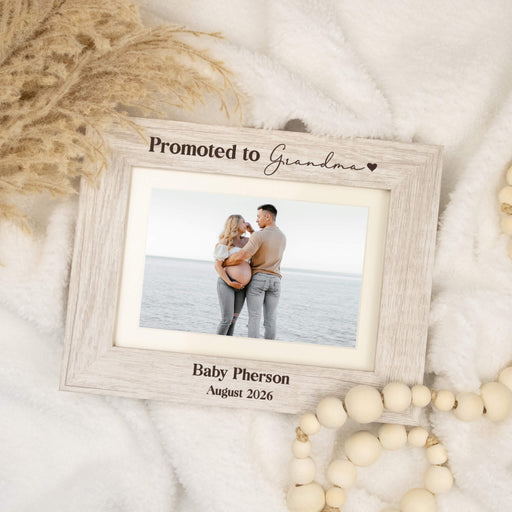 Horizontal rustic white engraved picture frame that says "Promoted to Grandma" on a white boho background