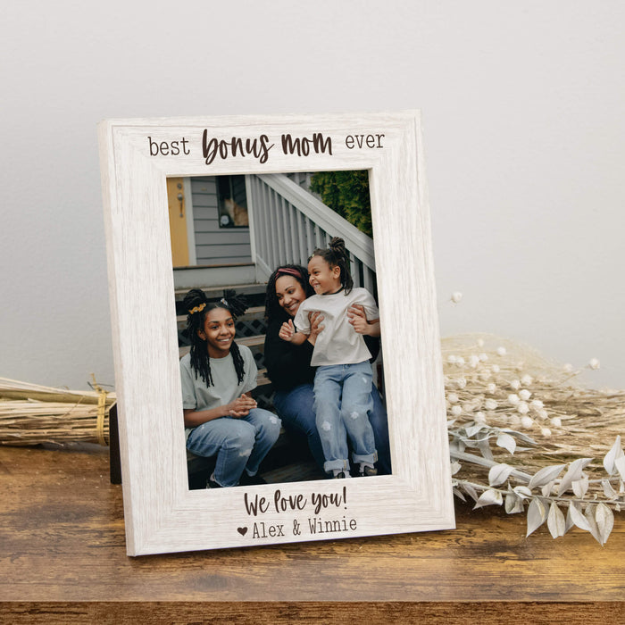 White photo frame with a family photo and text on a wooden surface.