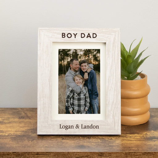 White wooden photo frame with a family photo and text on a wooden surface with a plant in the background