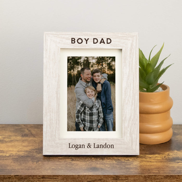 White wooden photo frame with a family photo and text on a wooden surface with a plant in the background