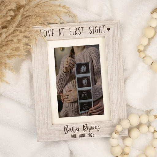 Wooden photo frame with 'Love at First Sight' and 'Baby Rippey Due June 2025' text, featuring a photo of a couple holding a baby bump.