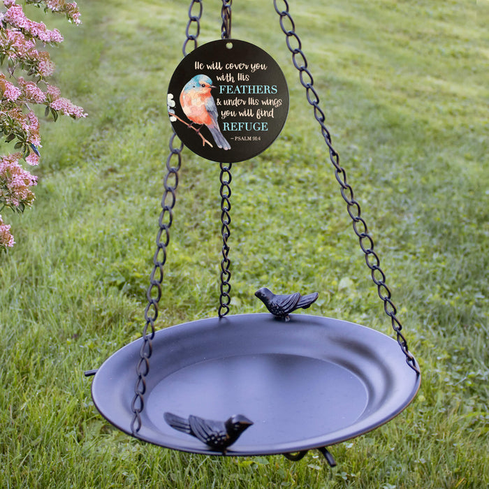 Decorative bird bath with hanging chain and bird design on a grassy background