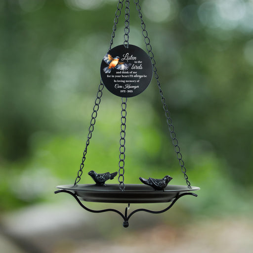 Decorative bird feeder with a black circular sail featuring birds and text, hanging against a blurred green background for memorial gift
