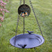 Decorative bird bath with hanging chain and bird design on a grassy background