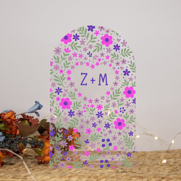 clear acrylic arch shaped flower vase with initials of couple inside a heart made out of flower pattern 