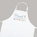 White apron on a gray background that has "loved beyond measure" and baking tools printed on it