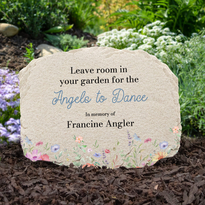 Memorial stone with floral design and text in a garden setting