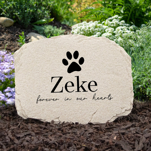 Custom pet memorial garden stone personalized with pet's name below a dog paw print sitting in a garden