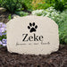 Custom pet memorial garden stone personalized with pet's name below a dog paw print sitting in a garden