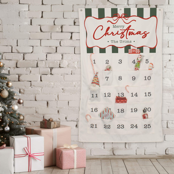 A festive Christmas advent calendar labeled 'Merry Christmas - The Urims' hanging on a white brick wall, with numbered fabric pockets and small holiday decorations. A decorated Christmas tree and wrapped gift boxes are visible on the left.
