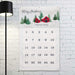 A personalized Christmas advent calendar for the 'Newman Family' hanging on a white brick wall. The calendar features a festive winter illustration at the top with 'Merry Christmas' and the family name, followed by 25 numbered pockets.