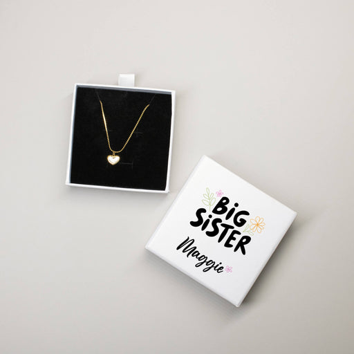 Gold necklace in a box with 'Big Sister' on a light gray background