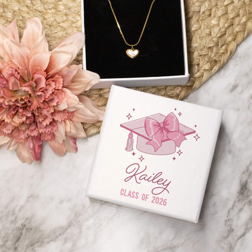 Jewelry box with 'Class of 2026' design, heart-shaped necklace, and pink flower on marble surface
