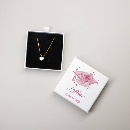 Gold heart-shaped opal necklace in a black display with a white box featuring 'Lillian Class of 2026' design on a light gray background.